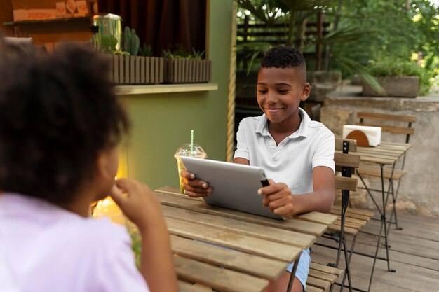 Close up kid sitting at table with tablet