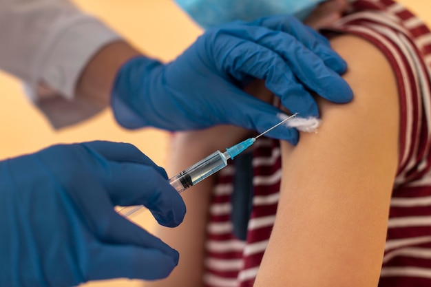 Free photo close up kid with face mask getting vaccine