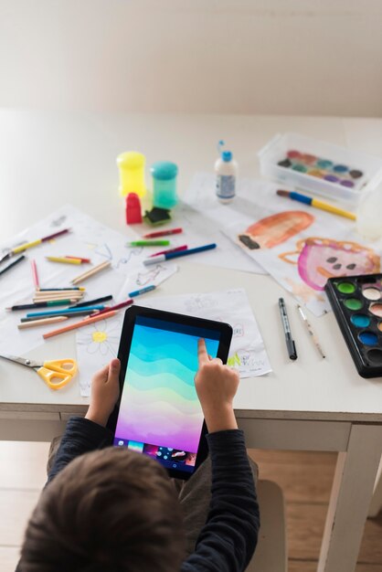 Close-up kid with tablet and pencils