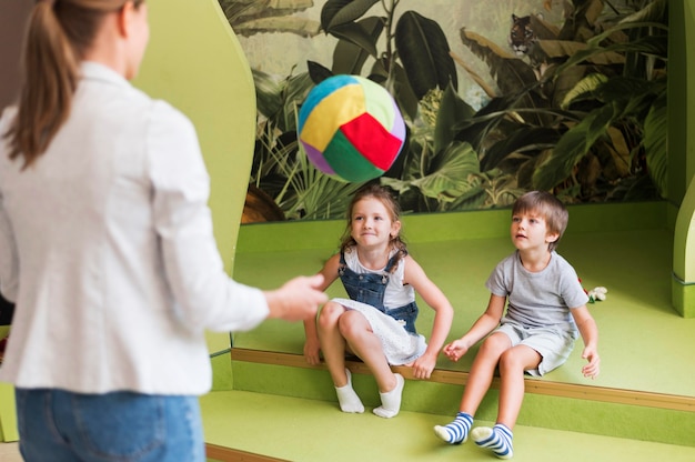 Бесплатное фото Дети крупным планом и учитель играют с мячом