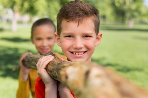 Free photo close up kids carrying log