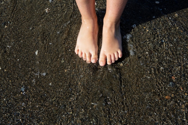 Крупным планом детские ноги на пляже