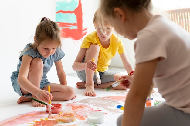 Free photo close up kids painting together indoors