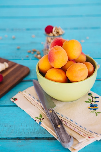 Free photo close-up of knife and fresh peach in bowl on napkin