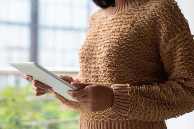 Close-up of lady in knitted sweater watching video on tablet