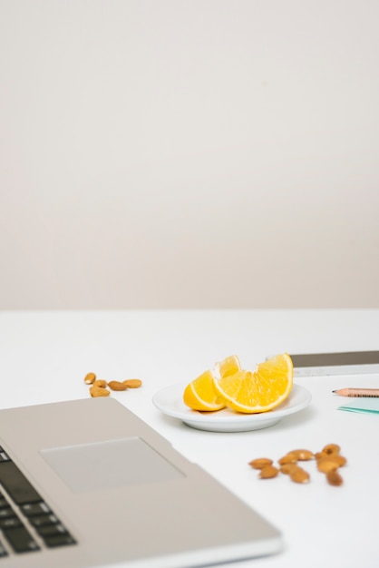 Close-up of laptop; almond; and sweet lime on desk