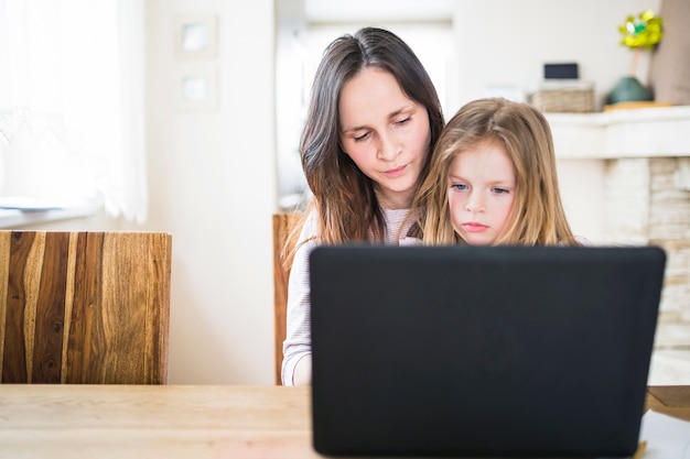 Foto gratuita primo piano del portatile davanti alla madre con sua figlia