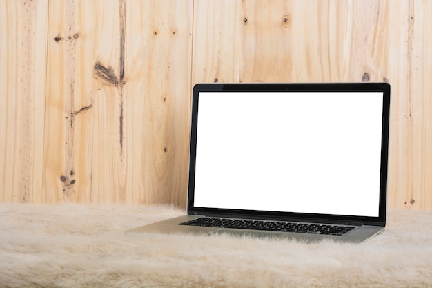 Close-up of laptop on soft fur in front of wooden wall