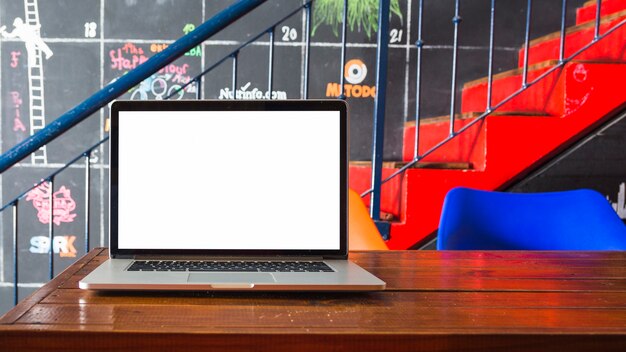 Close-up of laptop on wooden desk in front of staircase