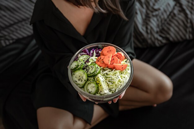 Close up of a large bowl with freshly prepared vegetable salad in female hands.