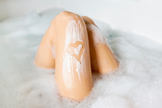 Close-up legs in bathtub with foam