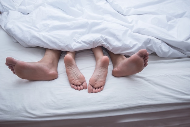 Close up legs of couple in bed