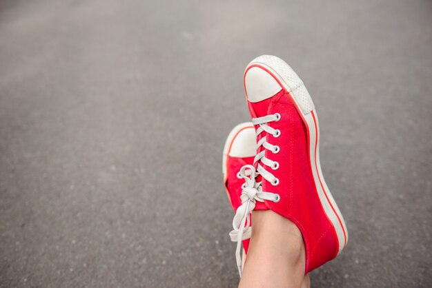 Close up of legs in red keds lying on asphalt.