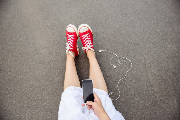 Close up of legs in red keds lying on asphalt.