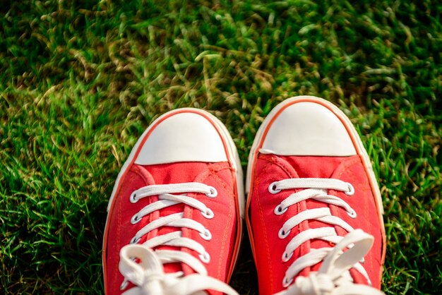 Close up of legs in red keds lying on grass.