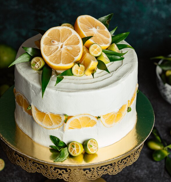 Close up of lemon cake topped with lemon and small green lemons