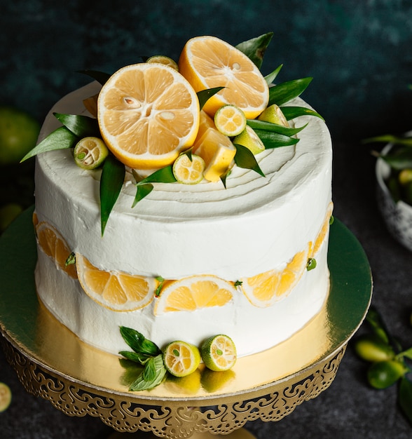 Close up of lemon cake topped with lemon and small green lemons