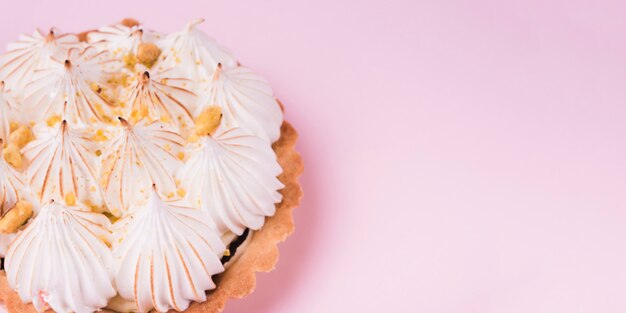 Close-up of a lemon tart with italian meringue on pink backdrop