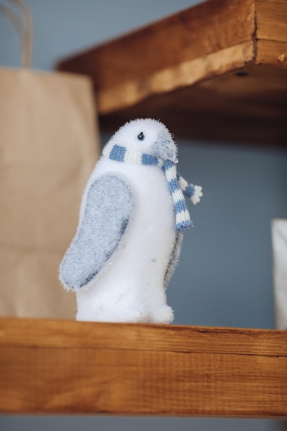 Free photo close-up of light blue toy penguin on brown wooden shelf.