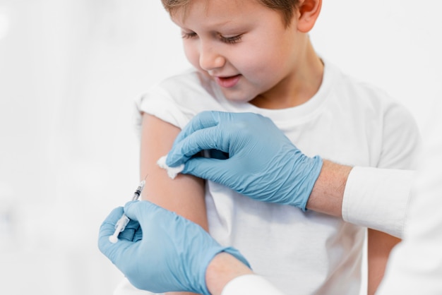 Бесплатное фото Крупным планом маленький мальчик получает вакцину