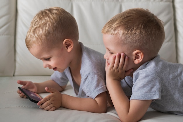 Close-up little brothers playing on phone