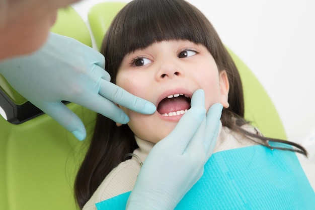 歯科医が歯を調べている少女のクローズアップ。