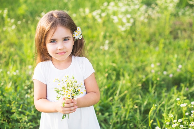 초원에서 흰 꽃 다발을 들고 어린 소녀 클로즈업