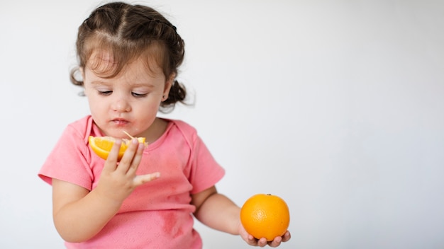 Bambina del primo piano che esamina le sue arance