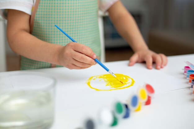 Close-up little girl with apron painting