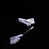 Free photo close-up of magician performing trick on playing card with magic wand