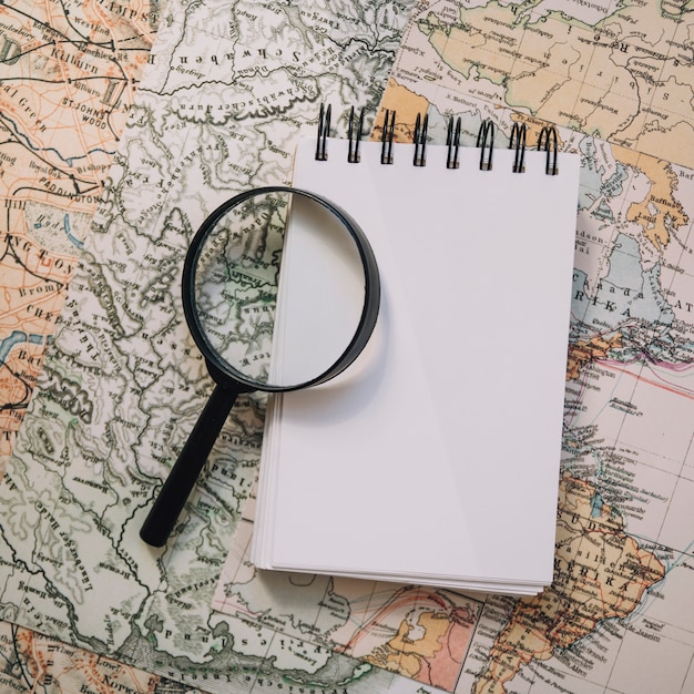 Close-up magnifying glass and notebook on map