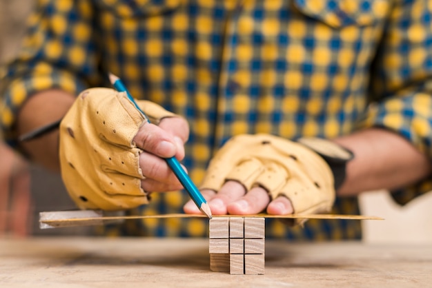 Foto gratuita primo piano della mano di un carpentiere maschio che fa misura sul blocco di legno