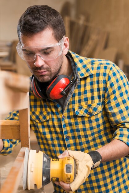 Close-up of a male carpenter at work polishing wood using orbit sander