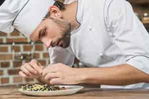 Foto gratuita primo piano del cuoco unico maschio che prepara il piatto degli spaghetti