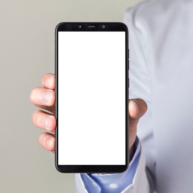 白い画面表示を持つスマートフォンを示す男性医師の手のクローズアップ