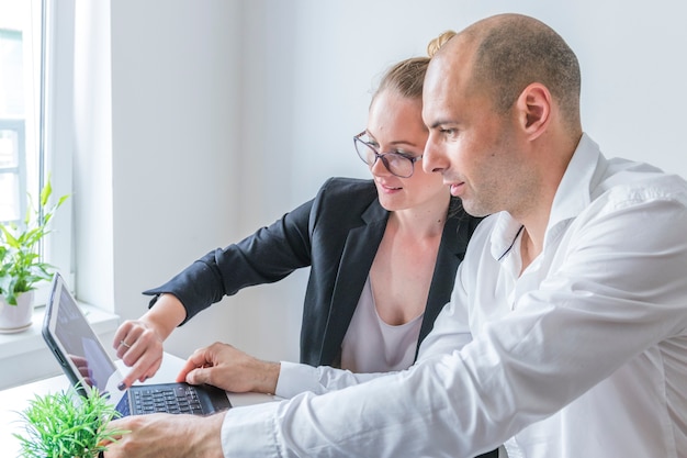 Close-up of male and female businesspeople working on laptop at workplace