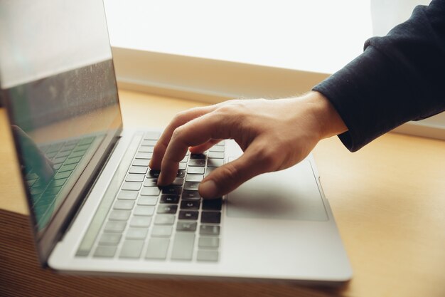 ノート パソコンでビジネス ドキュメント、メモ、または検索キーを入力する男性の指のクローズ アップ