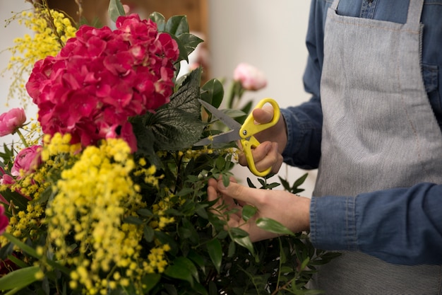 Free photo close-up of male florist cutting the leaves of bouquet