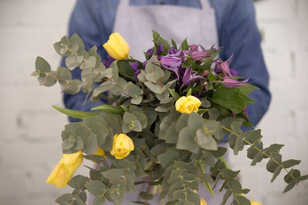 手に美しい花の花束を示す男性の花屋のクローズアップ