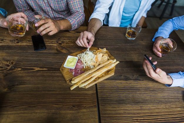 Close-up of male friends enjoying snack with whiskey