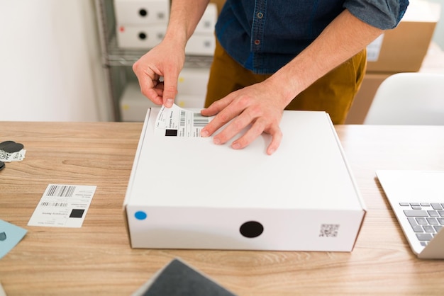 Free photo close up of male hands putting a shipping label on a package and arranging online customers' orders