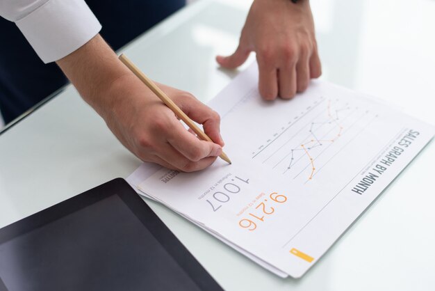 Close-up of male hands writing on sales report in office