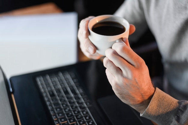 Tazza di caffè maschio della tenuta del primo piano