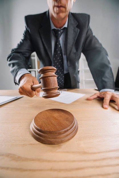 Close-up of male judge giving verdict by hitting gavel at desk