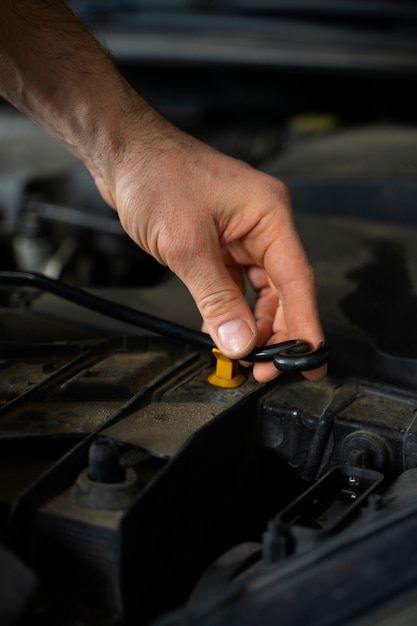 Foto gratuita primo piano del meccanico maschio che lavora nell'officina riparazioni auto sull'automobile