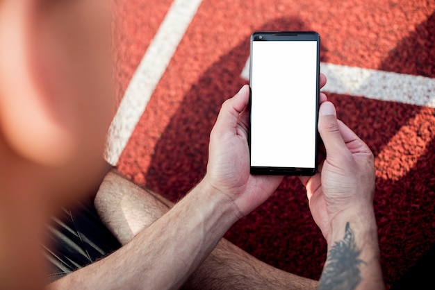 Close-up of male sportsperson holding mobile phone with white screen display