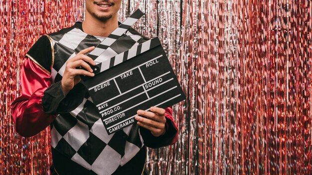 Close-up male with film slate at carnival party