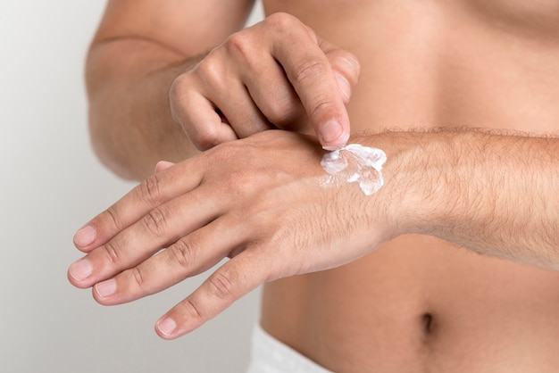 Close-up of man applying cream on hand