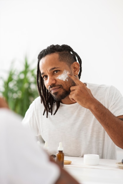 Free photo close up man applying face cream