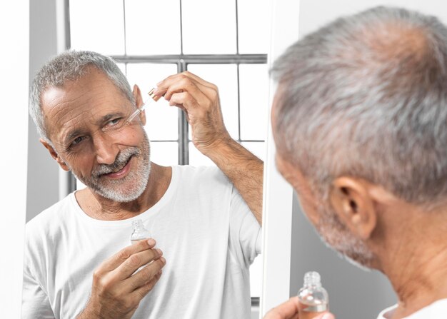 Close-up man applying face serum